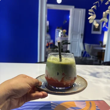 A layered matcha drink in a bright blue Berlin café